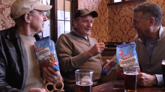 A group of men enjoying Herr's Sourdough pretzels in a pub