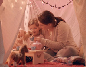 Mom and daughter playing together inside a blanket fort
