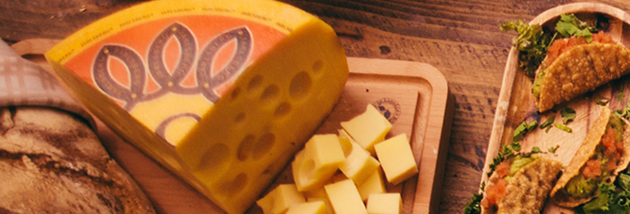 Part of a Jarlsberg cheese wheel and cheese cubes on a cutting board