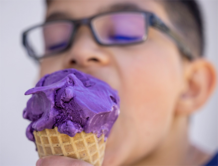 Person eating an ube ice cream cone